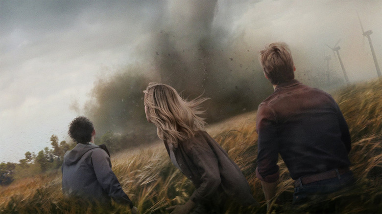 A trio stands staring at a tornado in a field in Twisters